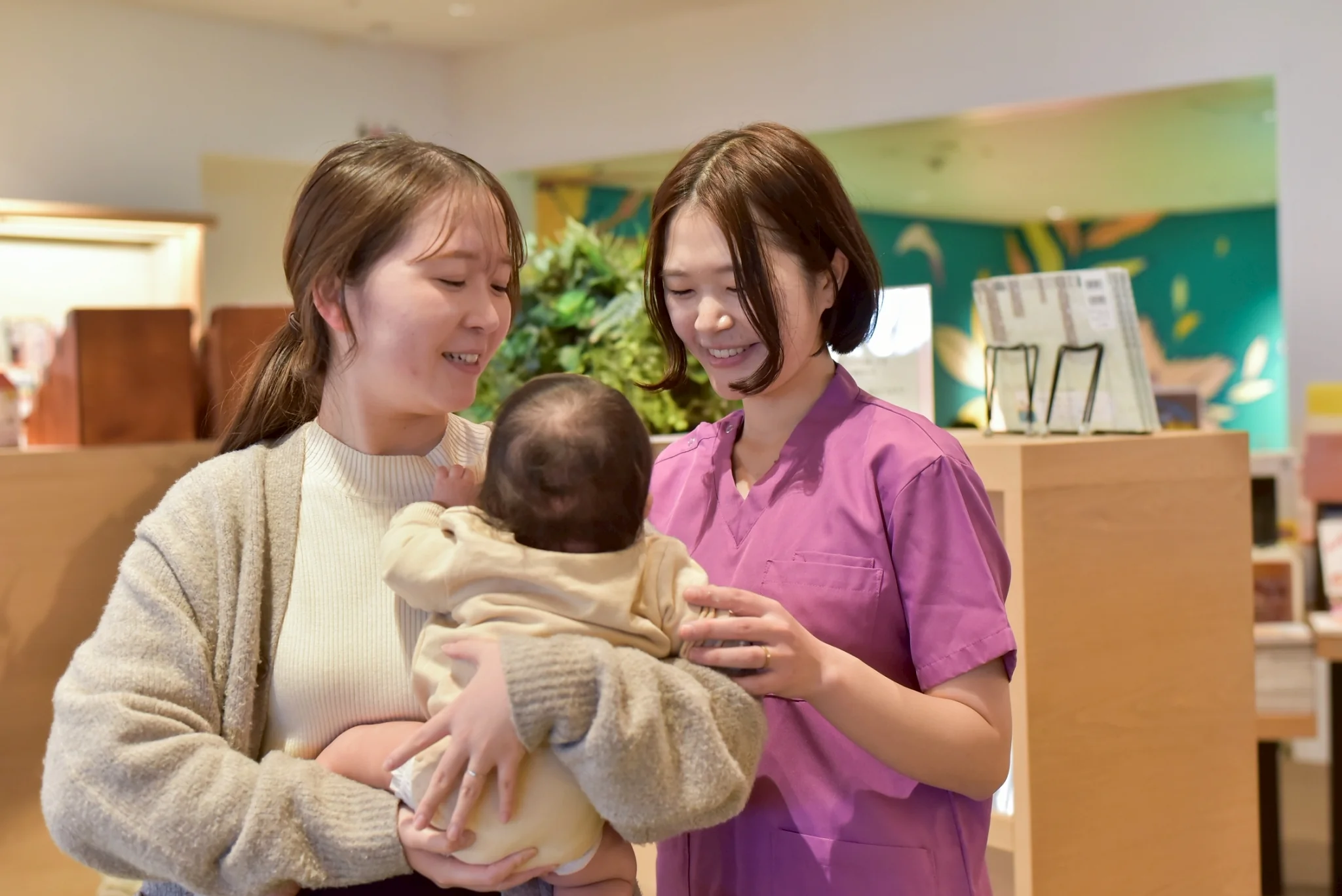 助産師に赤ちゃんを抱いてもらいながら笑顔で話すお母さん